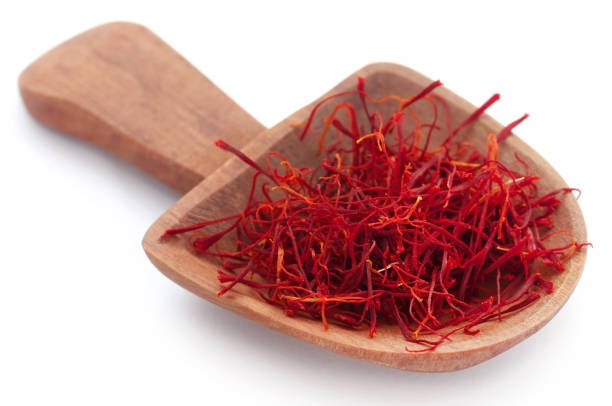 Saffron in a wooden scoop over white background