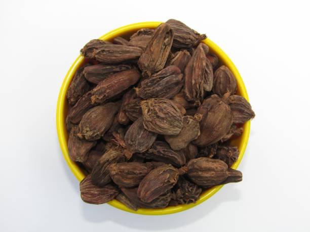 Black cardamom in a bowl on white background