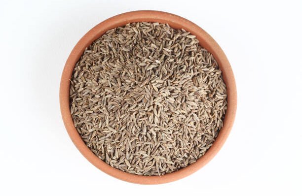 Cumin seeds into a bowl isolated in white background