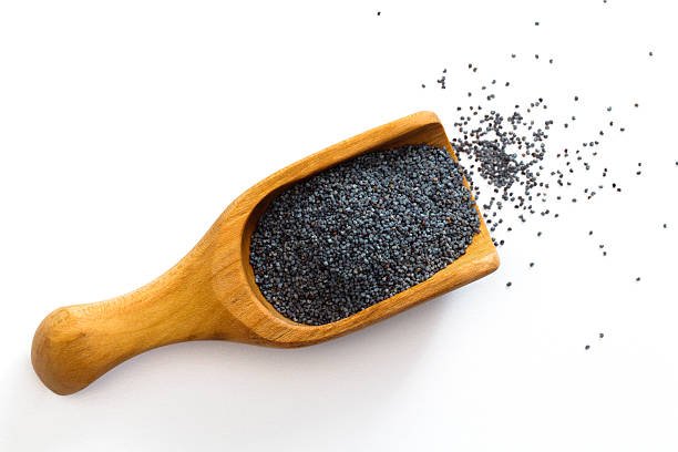 "Poppy seeds spill from a wooden scoop, isolated on white background"